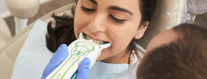 close up of a dentist using a digital scanner on a woman's teeth