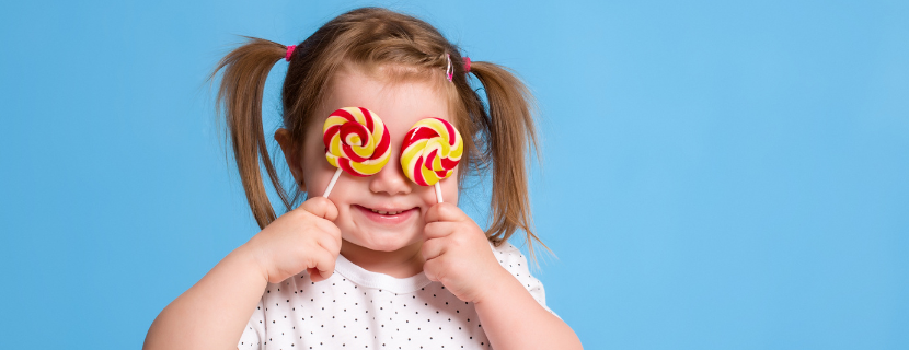 young child with bunches holding up two swirly lollipops in front of her eyes