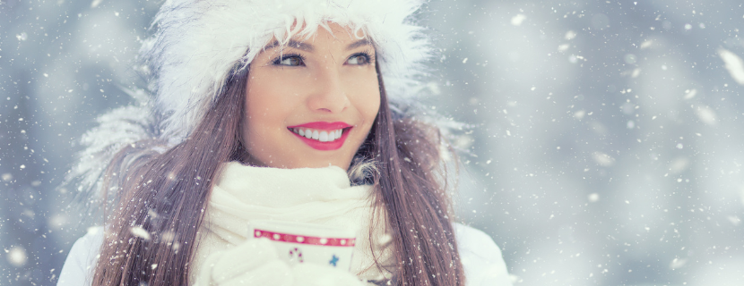 woman standing in the snow with bright, white teeth and red lipstick, dressed for winter