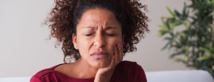 Woman holding mouth in pain with eyes closed