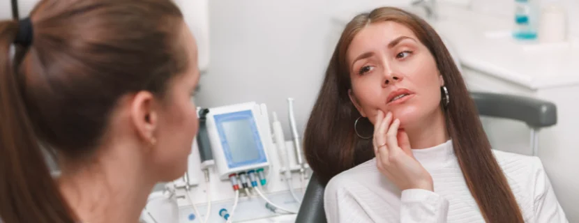 Woman lying on dental chair with toothache talking to dentist